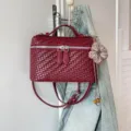 Dettaglio della borsa a mano in pelle intrecciata rosso scuro con cerniere e ciondolo carino. - Stile Con Ciondolo / Rosso