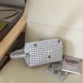 Detailansicht einer weiß karierten Kosmetiktasche mit schwarzen Stickereien für Reisen. - Schwarz Kariert