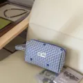 Detailansicht der blau-weißen karierten Kosmetiktasche mit Tragegriff und süßer Schleifenstickerei. - Kariertes Dunkelblau