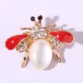 Rhinestone bee brooch detail, gold metal frame, red enamel wings, and pearl abdomen. - Red