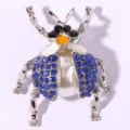 Vintage beetle brooch featuring vibrant blue rhinestones and a large pearl body in silver tone. - Blue