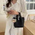 Borsa a secchiello nera da donna con ciondolo a forma di orsetto e chiusura, tracolla. - Con Ciondolo / Nero