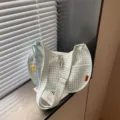 Dettaglio della borsa a tracolla in tela a quadri verde chiaro con zip e cinturino. - Con Ciondolo / Verde