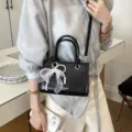 Black woven leather women handbag with pearl bow accessory, stylish single shoulder bag. - Pendant Included / Black