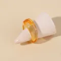 Amber resin ring detail showing transparent glossy surface and minimalist geometric round shape. - One Size / Amber / Yellow