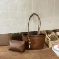 Λεπτομερής όψη κομψής πλεγμένης δερμάτινης τσάντας tote με ασορτί θήκη σε εσωτερικό χώρο. - Καφέ με μενταγιόν