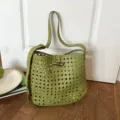Dettaglio borsa a spalla in pelle intrecciata verde, motivo traforato con fibbia in corno. - Verde