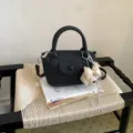 Vue détaillée d'un sac seau noir chic en cuir avec poignée et joli pendentif ours. - Avec Pendentif / Noir