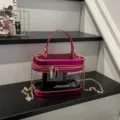 Bolso neceser transparente de mujer con ribete rosa metálico y elegante correa de cadena dorada. - Con Colgante de Encaje / Rosa rojo