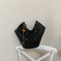 Detailaufnahme der schwarzen Lasercut Schultertasche mit schicken Holperlen-Griffen. - Mit Anhänger / Schwarz