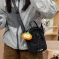 Close-up detail of casual black crossbody sling bag with cute plush pendant and drawstring. - Persimmon Kitten Pendant / Black