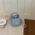 Detailansicht der hellblauen Leder-Beuteltasche mit geflochtenem Griff und Schultergurt. - Basisstil / Blau
