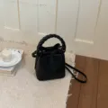 Schwarze Leder-Beuteltasche Detailaufnahme mit geflochtenem Griff und hochwertiger Textur. - Basisstil / Schwarz