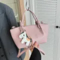 Sac à bandoulière en cuir rose avec poignées nouées et charm cheval pour tous les jours. - Rose avec pendentif