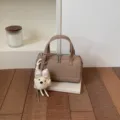 Close-up detail of the stylish khaki pillow handbag featuring a cute plush puppy keychain. - With Pendant / Khaki