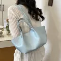 Detail shot of a minimalist light blue tote bag with double straps worn by model indoors. - Blue