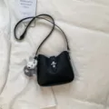 Minimalistische schwarze Leder-Umhängetasche mit Metallverschluss und niedlichem Plüsch-Häschen. - Mit Puppenanhänger / Schwarz
