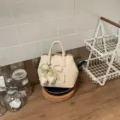 Nahaufnahme Detail des beigen Eimerbeutels mit elegantem Perlen Tulpen Anhänger Griff. - Weiß Mit Anhänger