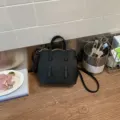 Schwarze kleine Bucket Bag aus Leder mit Tragegriffen und verstellbarem Schulterriemen. - Schwarz