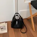 Bolso tipo cubo de cuero negro con asa superior y correa de hombro, elegante y chic. - Negro