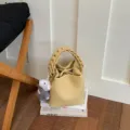 Elegante gelbe Damen Beuteltasche mit geflochtenem Griff und süßem Plüsch Anhänger. - Anhänger-Stil / Gelb