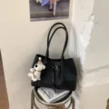 Detail view of the black woven tote bag with dual straps, bucket design, and cute bear charm. - Black With Pendant