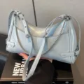 Borsa a tracolla in pelle verniciata azzurra con catena e fibbie da donna. - Blu