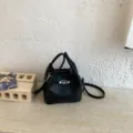 Bolso cubo negro de cuero granulado, variante con asa superior y correa de hombro. - Negro