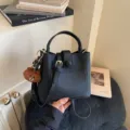 Nahaufnahme Detail der stilvollen schwarzen Leder Beuteltasche mit süßem Bären Anhänger. - Mit Anhänger / Schwarz