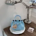 Hellblaue geflochtene Ledertasche stilvolle Beuteltasche mit Henkel und Bärenanhänger. - Mit Anhänger / Blau