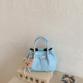 Detailed view of light blue woven leather bucket handbag with cute plush bear keychain charm. - With Pendant / Blue