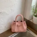 Chic pink woven leather handbag with top handles and a trendy front buckle accent. - No Pendant / Pink