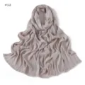 Detail view of the soft crinkled long scarf with frayed edges in light grey neutral tone. - Style 12