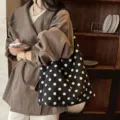 Borsa a tracolla in pelle scamosciata a pois neri, variante capiente alla moda da donna. - Nero