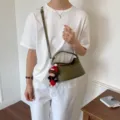 Green woven leather shoulder bag, stylish autumn dumpling bag with chic doll pendant accessory. - Green