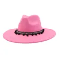 Pink suede fedora hat detail showcasing woven band and black pom-pom decorations closely. - Barbie Pink