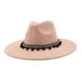 Chic pink suede fedora hat featuring black white geometric band and playful pom poms. - Champagne