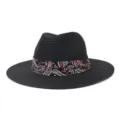 Detailed shot of a black straw fedora hat featuring a colorful paisley pattern ribbon band. - Black