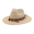 Detail view of woven straw sun hat, featuring ethnic style colorful ribbon, tassels and shells. - Beige