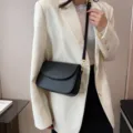 Minimalistische schwarze Umhängetasche aus Leder, schicke Klapptasche mit goldener Hardware. - Schwarz