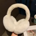 Detailed shot of white fluffy winter earmuffs, soft plush texture, cozy cold weather accessory. - White
