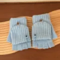 Close-up detail of light blue knitted convertible half-finger gloves with button flip cover design. - One Size / Blue