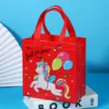 Red non-woven gift bag featuring a cute unicorn and balloon cartoon print for parties. - Red