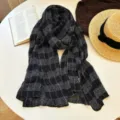 Detailed view of the stylish black and white plaid scarf, showcasing soft texture and cozy knit. - Black