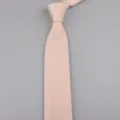 Primo piano sulla trama a maglia fine e sulla punta affilata di un elegante cravatta rosa chiaro. - Beige