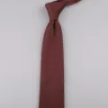 Dettaglio cravatta in maglia rosso vino primo piano, consistenza premium, accessorio elegante. - Caffè