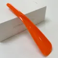 Bright orange plastic shoehorn with a long handle and hanging hole for convenient daily use. - Orange