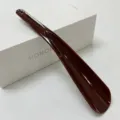 Brown plastic shoehorn with hanging hole, portable long handle helper for easy daily footwear wear. - Brown