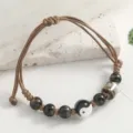 Brown braided cord bracelet featuring black beads and a ceramic yin yang charm. - Bagua Style