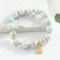 Bracelet de perles en céramique de Jingdezhen avec espaceurs dorés et pendentif chance. - 10mm / Bleu Clair Beige